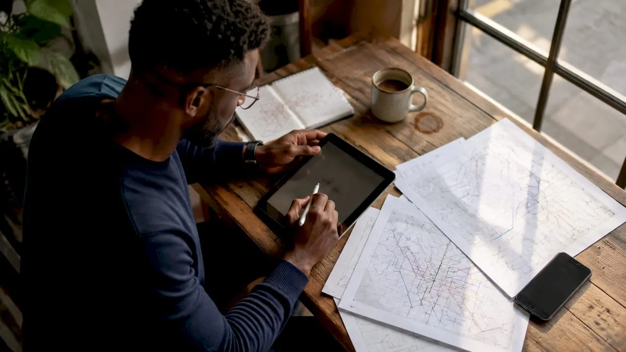 Planner's hands with network topology documents and tablet