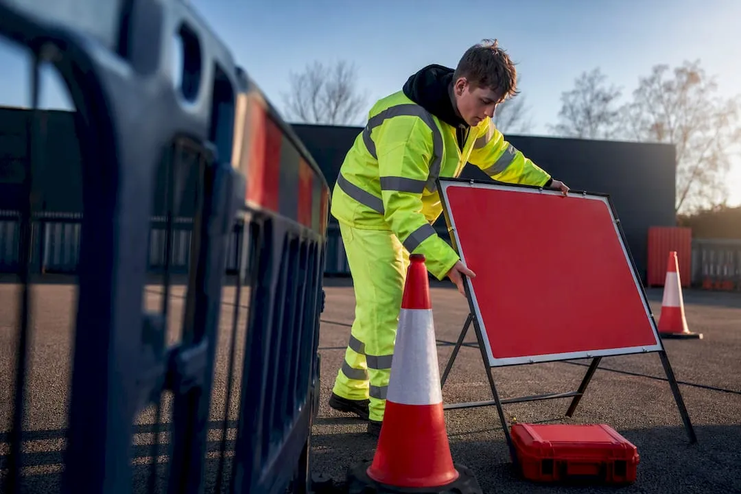 Trainee positioning temporary traffic management signs